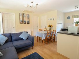 A living room with a dining area and kitchen appliances at 15 The Dell Mundesley