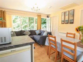 A living room with a sofa and dining area at 15 The Dell Mundesley