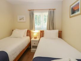 A bedroom with two beds and a bedside table at 15 The Dell Mundesley