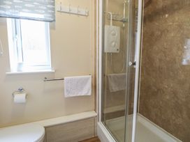 A bathroom with a shower and towel rail at 15 The Dell Mundesley