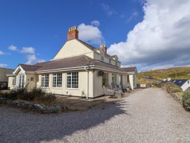 A large cream house with multiple windows and a patio with chairs along a gravel driveway at Orme Villa in Llandudno