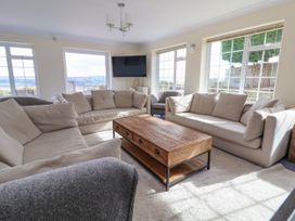 A sitting room with beige sofas wooden coffee table armchairs and large windows at Orme Villa in Llandudno