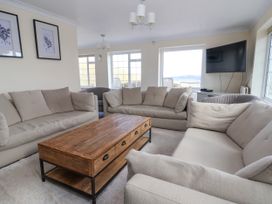 A living room with beige sofas wooden coffee table wall art and a wall-mounted television at Orme Villa in Llandudno