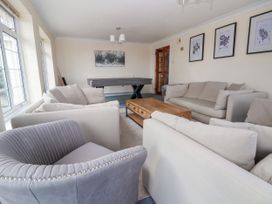 A living room with sofas armchair wooden coffee table pool table and framed pictures on the wall at Orme Villa in Llandudno