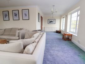 A living room with beige sofas framed botanical prints on the wall and a blue carpet at Orme Villa in Llandudno