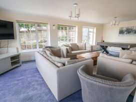 A living room with beige sofas a wooden coffee table blue carpet and a pool table at Orme Villa in Llandudno
