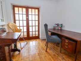 A room with a wooden desk, a gray chair, a yellow baby high chair, and wooden double doors at Orme Villa in Llandudno