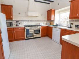 A kitchen with wooden cabinets a stove a dishwasher and a window at Orme Villa in Llandudno