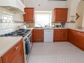 A kitchen with wooden cabinets a gas stove dishwasher and a window at Orme Villa in Llandudno