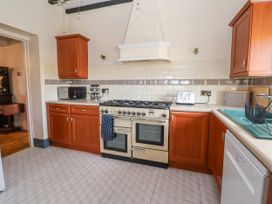 A kitchen with wooden cabinets a stove microwave toaster and dishwasher at Orme Villa in Llandudno