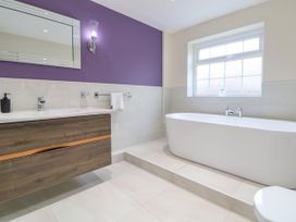 A bathroom with a freestanding bathtub sink with wooden cabinet and a window at Orme Villa in Llandudno