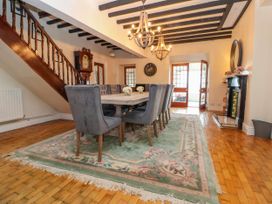 A dining room with a table and chairs on a rug under wooden beams at Orme Villa in Llandudno