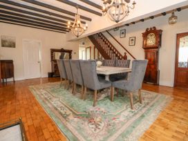 A dining room with a wooden table surrounded by gray chairs on a floral rug and wooden staircase at Orme Villa in Llandudno