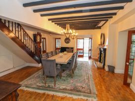 A dining room with a long table surrounded by chairs a staircase and a fireplace at Orme Villa in Llandudno