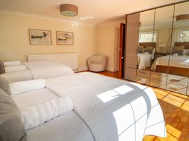 A bedroom with two beds with white linens a round chair two paintings and a mirrored wardrobe at Orme Villa in Llandudno