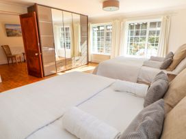 A bedroom with two beds, large wardrobe with mirrored doors, chair, and windows with curtains at Orme Villa in Llandudno