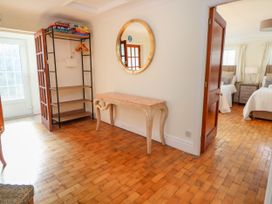 A hallway with a wooden floor a wooden table with a mirror above it and a shelf with board games and hangers at Orme Villa in Llandudno