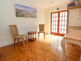 A room with two woven chairs and a small wooden table between them near double paneled wooden doors at Orme Villa in Llandudno