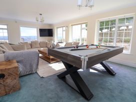 A living room with a pool table sofa coffee table and wall mounted television at Orme Villa in Llandudno