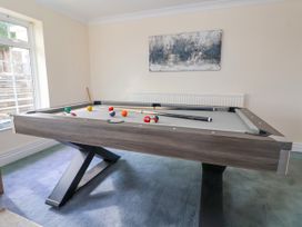 A game room with a pool table sticks and balls on the table a window and a painting on the wall at Orme Villa in Llandudno