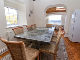 A dining room with a large rectangular table surrounded by woven chairs and a glass bowl on top at Orme Villa in Llandudno