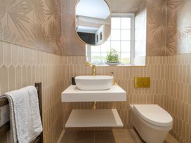A bathroom with a wall-mounted sink and mirror next to a window and a wall-mounted toilet at Orme Villa in Llandudno