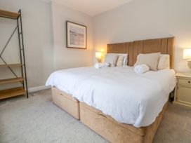 A bedroom with two beds pushed together with white bedding two bedside tables with lamps a wall shelf and a framed picture at Orme Villa in Llandudno