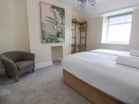 A bedroom with a double bed white linens an armchair a window and a wall painting at Orme Villa in Llandudno