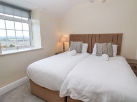 A bedroom with two single beds side by side with white bedding a window and a lamp on a bedside table at Orme Villa in Llandudno