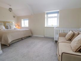 A bedroom with a double bed two windows a sofa and a white crib at Orme Villa in Llandudno