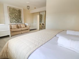 A bedroom with a large bed with rolled towels a beige sofa and a white crib at Orme Villa in Llandudno