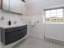 A bathroom with a black vanity cabinet and sink a mirror cabinet and a window showing an outdoor view at Orme Villa in Llandudno