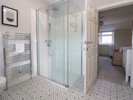 A bathroom with a glass shower enclosure a towel rack and patterned floor tiles at Orme Villa in Llandudno