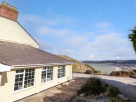 Exterior view of a house with large windows overlooking a coastal landscape and a curving beach at Orme Villa in Llandudno