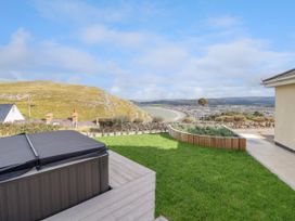 A garden with a hot tub lawn and a planter with a coastal view at Orme Villa in Llandudno