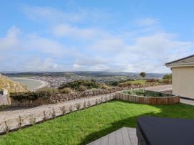 A garden with grass and a wooden planter overlooking a coastal town and hills at Orme Villa in Llandudno