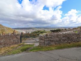 A metal gate between stone walls overlooking a town and coastline with hills in the background at Orme Villa in Llandudno