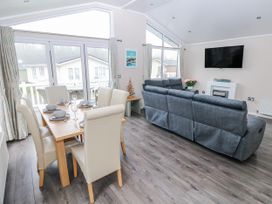 A living room with a dining area and television at Dono's Lodge, Stepaside near Kilgetty, Heritage Park