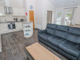 A living room with a kitchen area and a sofa at Dono's Lodge Stepaside near Kilgetty Heritage Park