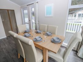 A dining room with a table set for six at Dono's Lodge Stepaside near Kilgetty Heritage Park