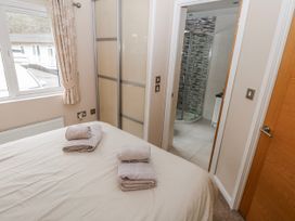 A bedroom with bed and towels on it at Dono's Lodge in Stepaside near Kilgetty, Heritage Park