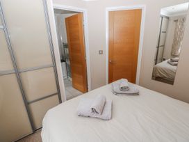 A bedroom with a bed and towels on blankets at Dono's Lodge, Stepaside near Kilgetty, Heritage Park
