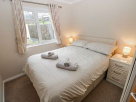 A bedroom with a bed and bedside table at Dono's Lodge, Stepaside near Kilgetty, Heritage Park