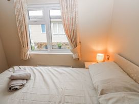 A bedroom with a bed and curtains at Dono's Lodge Stepaside near Kilgetty Heritage Park