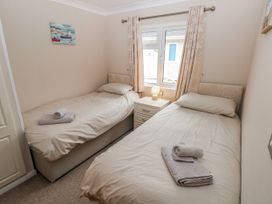 A bedroom with two beds and a bedside table at Dono's Lodge, Stepaside near Kilgetty, Heritage Park