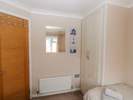 A bedroom with a mirror, wardrobe, and door at Dono's Lodge, Stepaside near Kilgetty, Heritage Park