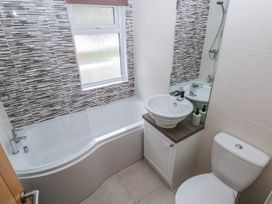 A bathroom with a bathtub, toilet, and sink at Dono's Lodge, Stepaside near Kilgetty, Heritage Park