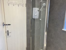 A shower with a door in a bathroom at 22 Longstone Park Beadnell