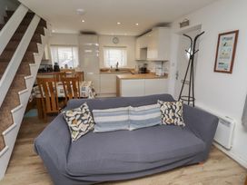 A living room with a sofa and kitchen area at 22 Longstone Park Beadnell