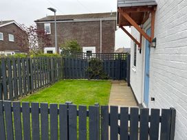 A garden with grass and a wooden fence at 22 Longstone Park Beadnell